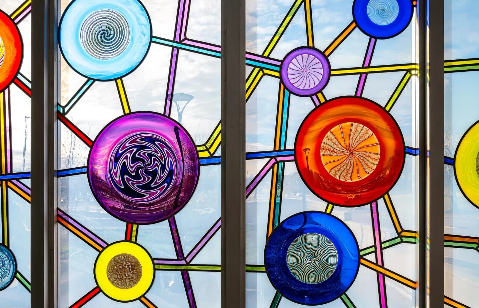 Stained glass window set with bright hand-blown rondels in a geometric pattern