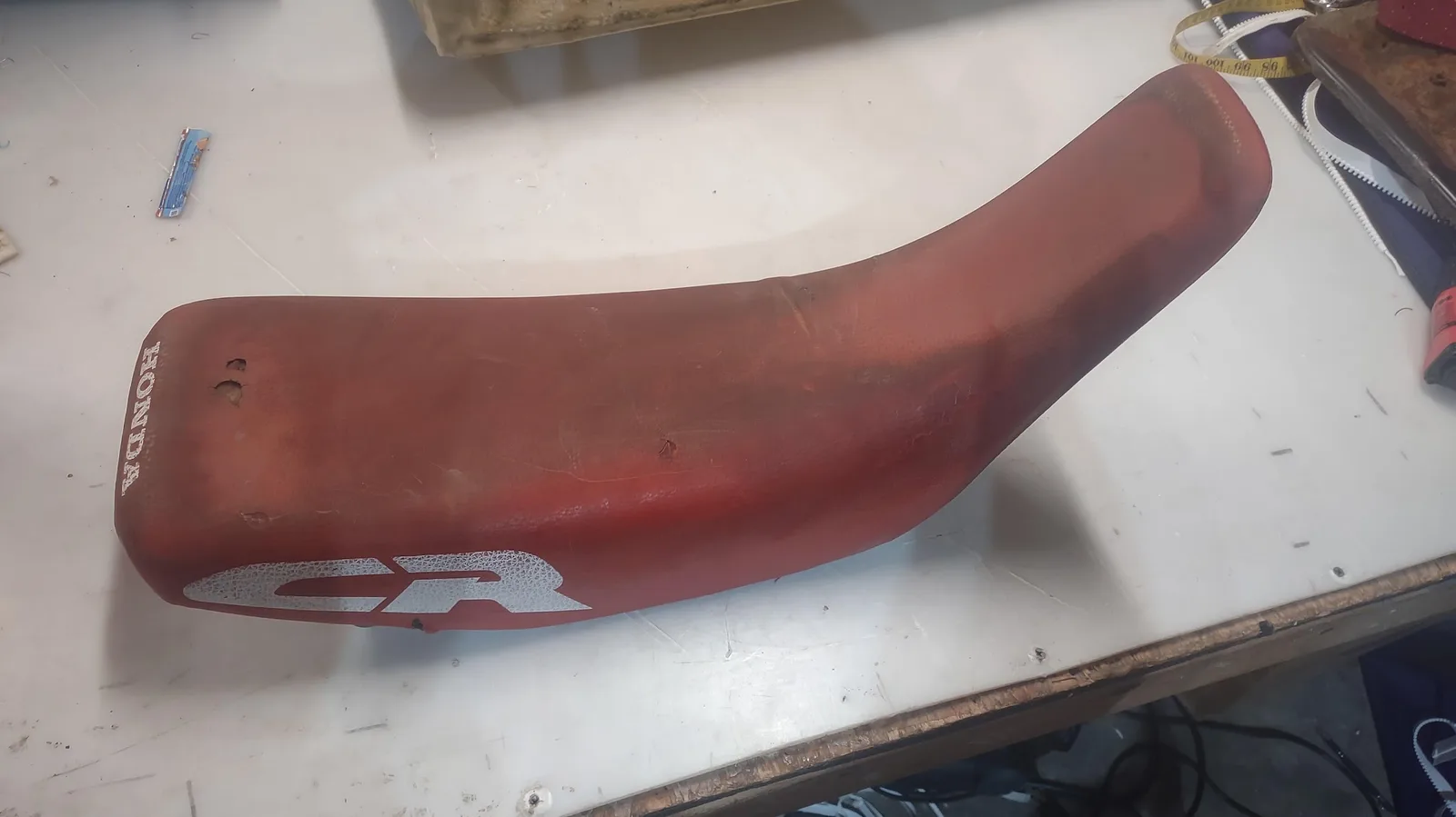 The same dirt bike seat before, worn and faded, by Matsu Upholstery