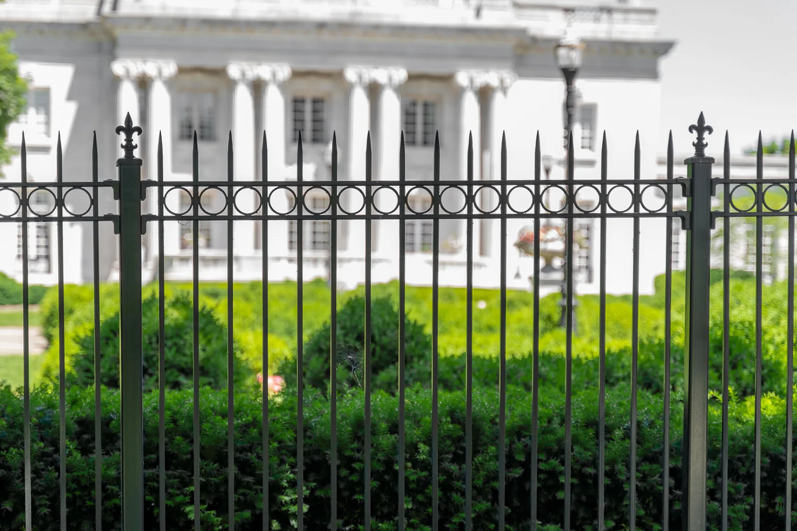 Ornamental iron fence before a white-columned mansion