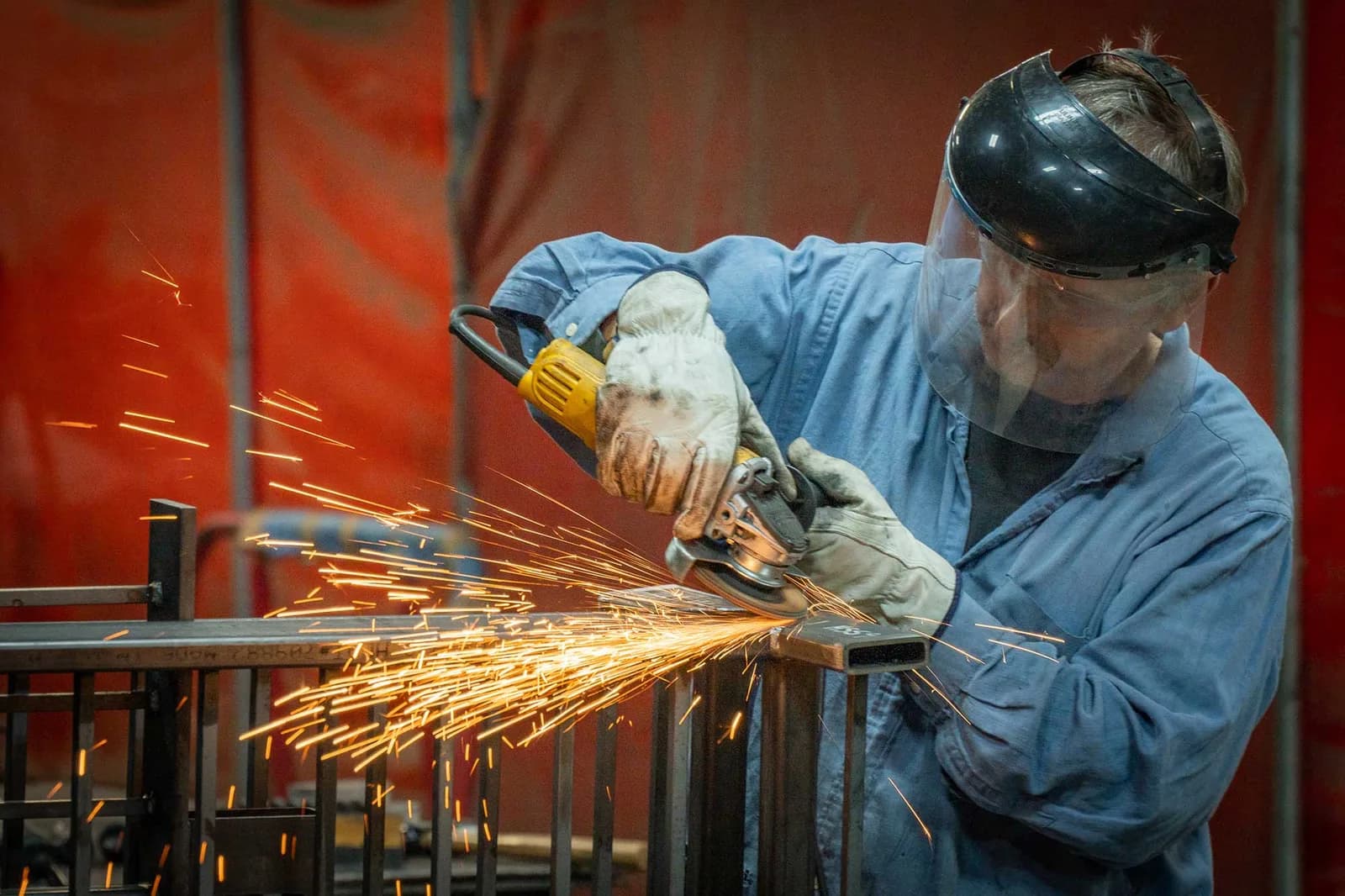 Stewart Iron Works metalworker grinding steel, sparks flying